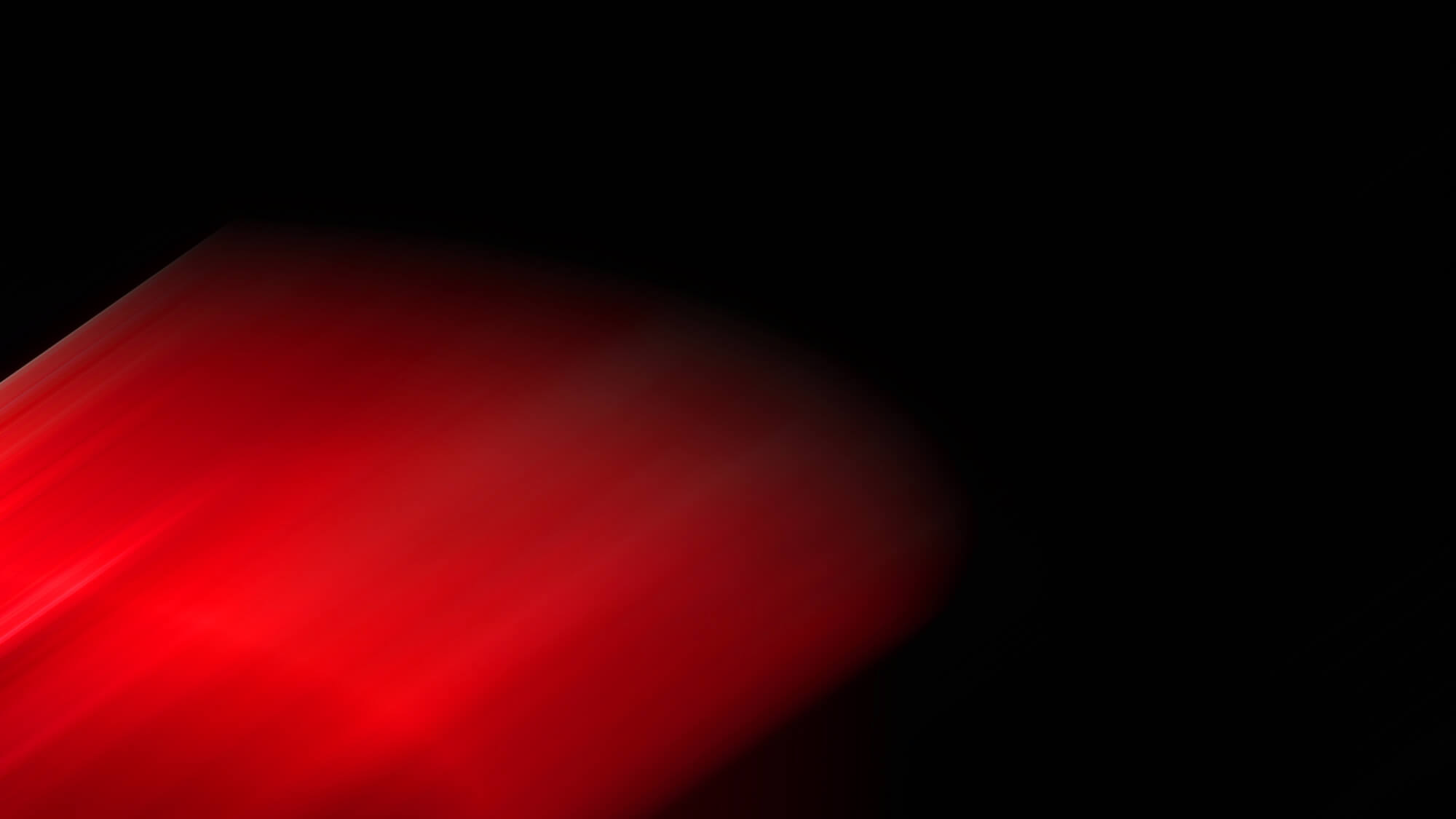 A streak of red light diagonally crosses a black background, creating a blurred and abstract visual effect.